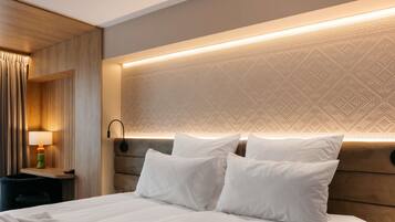 A hotel room with a large bed, a bedside table, a lamp, and a patterned headboard.