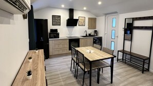 A modern kitchen with a dining area, wooden flooring, and built-in appliances. - Chez Fanf et Nanie (Isigny-sur-Mer)