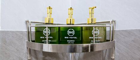 Une salle de bain avec un lavabo chromé et trois flacons de shampoing, de gel douche et de gel pour le corps de la marque Big Hotel.