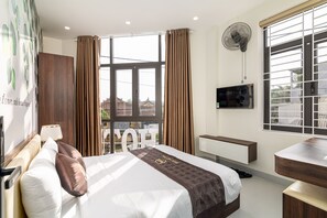 A hotel room with a large bed, a TV, a desk, and a balcony view. - BIG HOTEL (Hue)