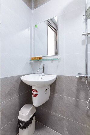 A bathroom with a white sink, a glass shelf above it, and a mirror. - BIG HOTEL (Hue)