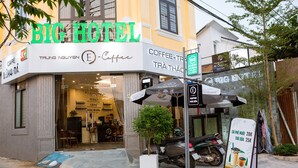 A hotel named BIGHOTEL with a coffee shop sign, a motorcycle parked outside, and a signboard with prices. - BIG HOTEL (Hue)
