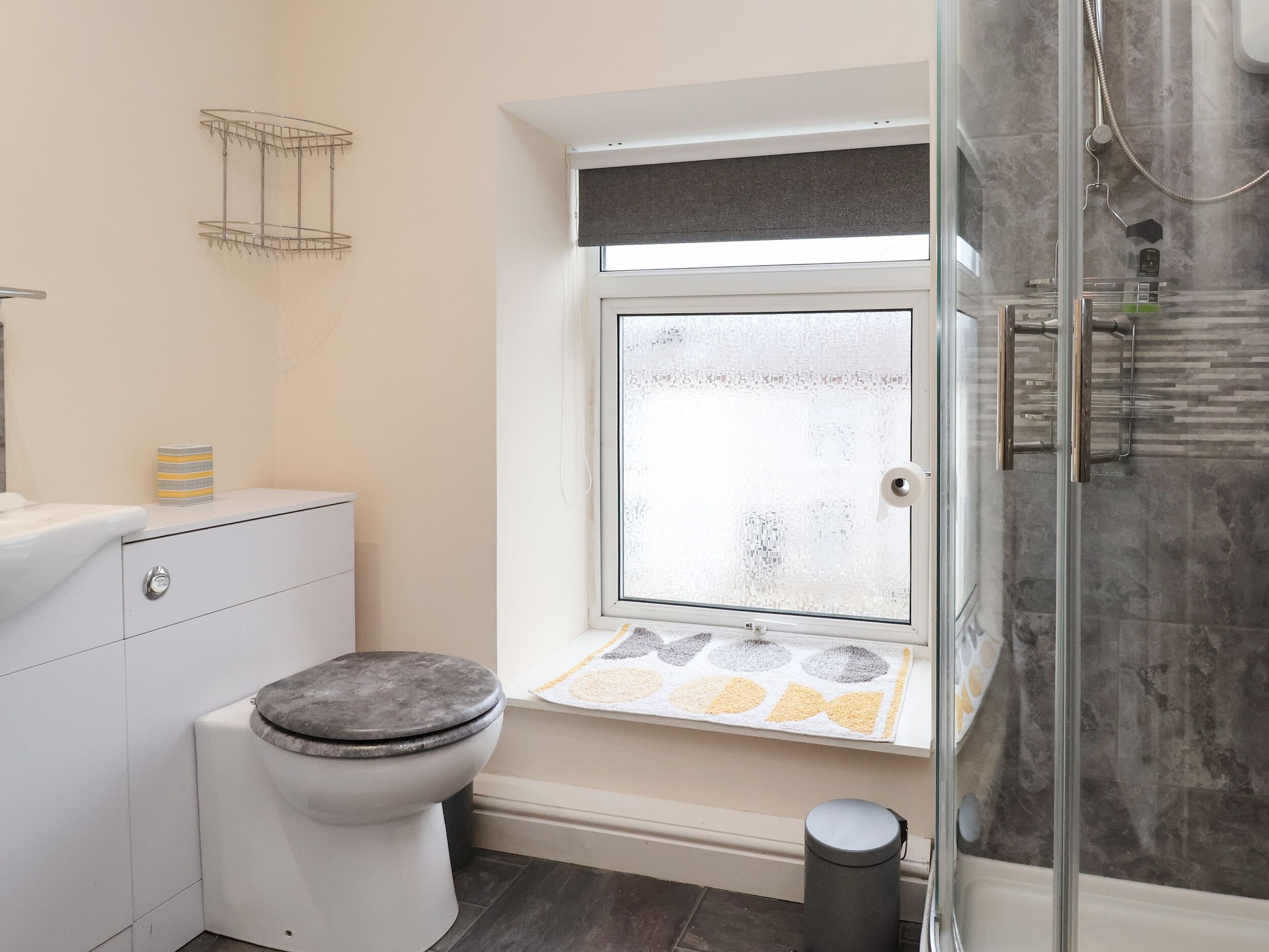 Une salle de bain équipée de toilettes, d’une douche et d’une fenêtre en verre dépoli.