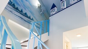 Een moderne trap met blauwe leuningen en een sfeervolle muurschildering erboven.