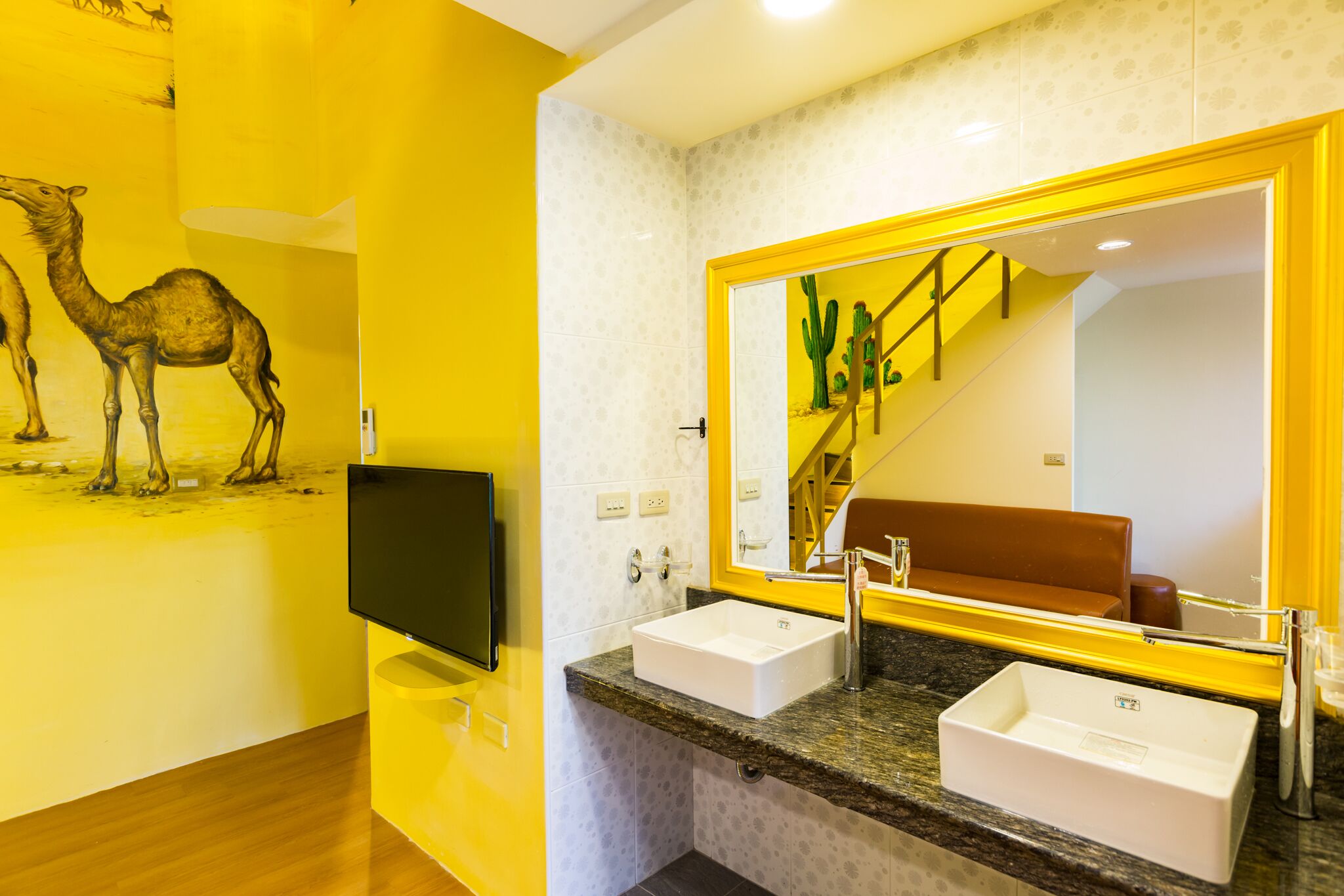 A modern bathroom with a large mirror, two sinks, and a television.