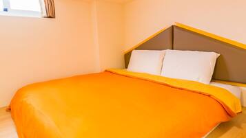 Una cama con colcha naranja y cabecera con detalle amarillo.