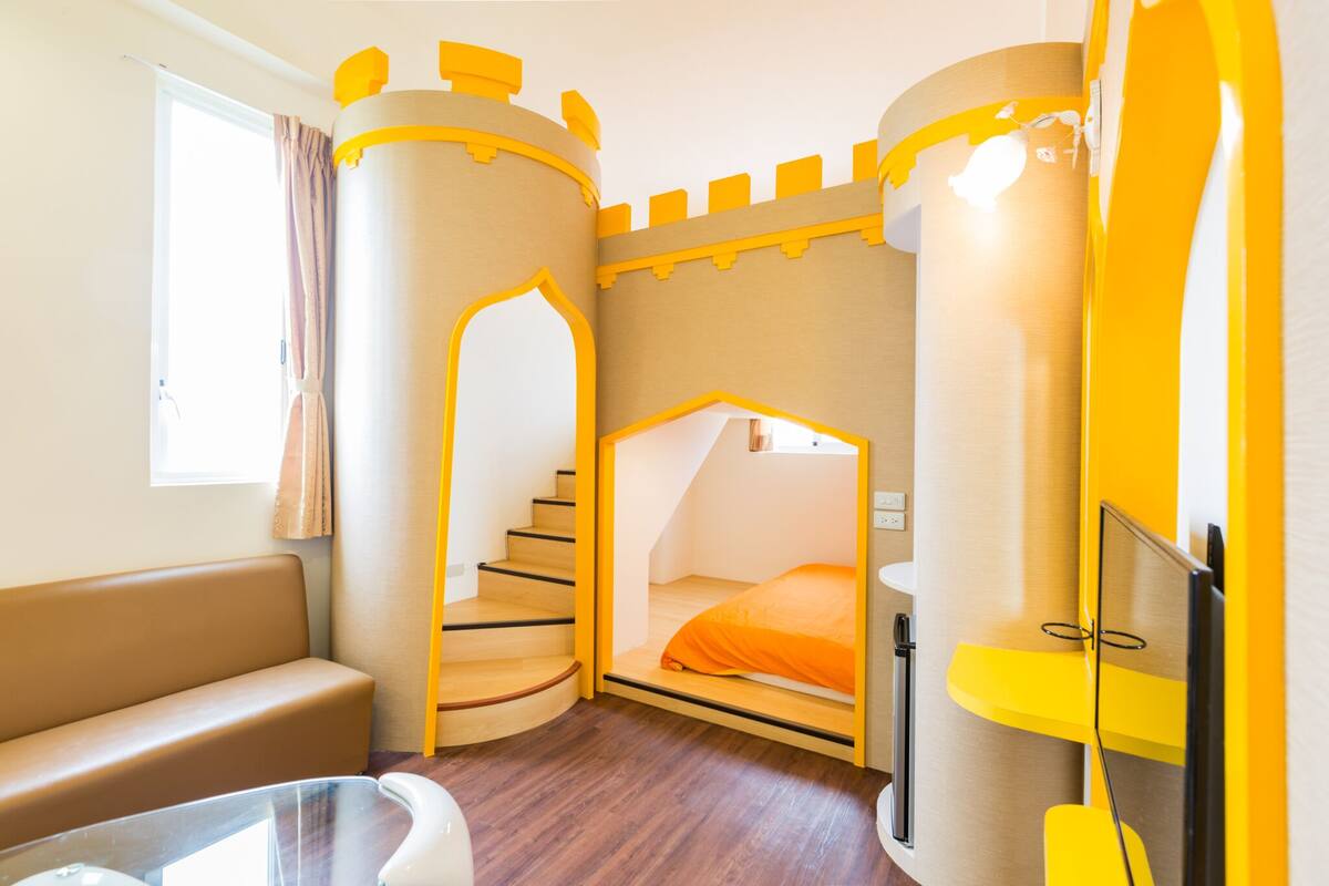 A bedroom with a castle-themed design, including a bed, a sofa, and a small table.