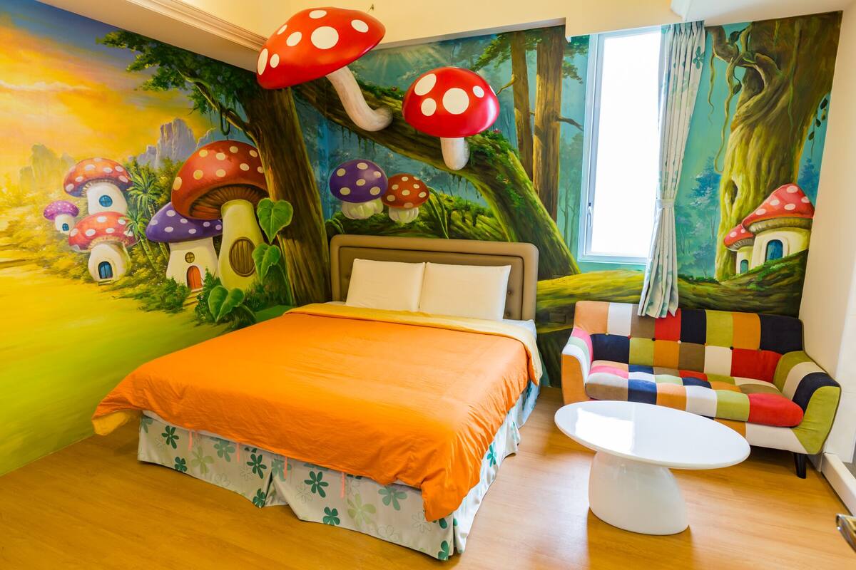 A bedroom with a bed, a colorful sofa, and a round table.