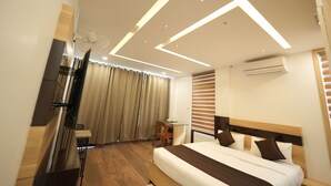 A modern hotel room with a large bed, a desk, and a TV. - Lush Hills by Benchmark (Vythiri)