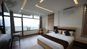 A modern bedroom with a large bed, a desk, and a balcony with a view. - Lush Hills by Benchmark (Vythiri)