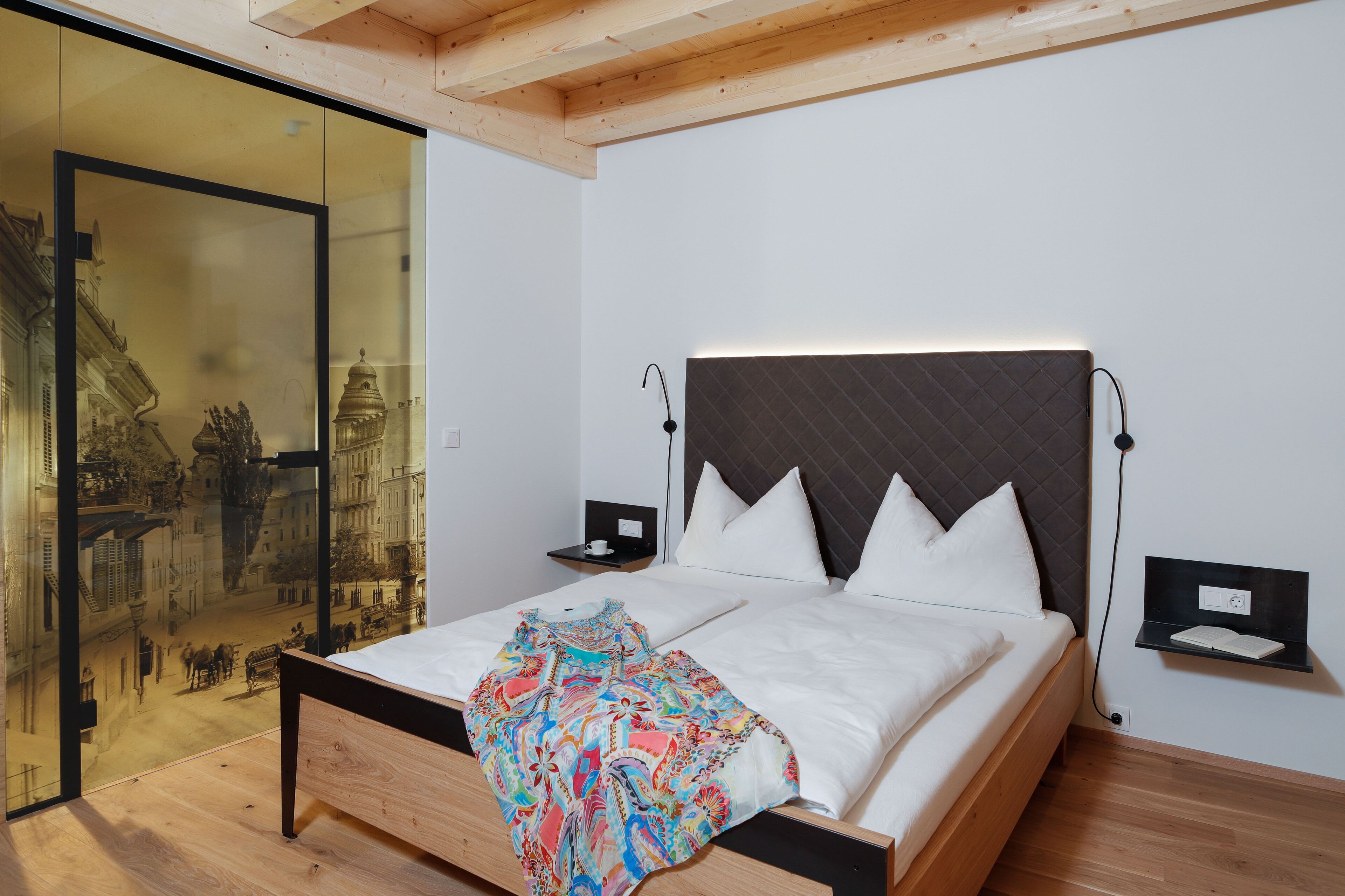 Quarto moderno com uma cama grande, uma parede de vidro com vista para a cidade e teto de madeira.