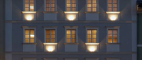 A multi-story building with illuminated windows and a cafe on the ground floor.