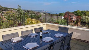 A dining table set outdoors with a view of a residential area and hills in the background.