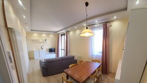 Una sala de estar moderna con una mesa de comedor de madera, un sofá gris y un televisor sobre un mueble.