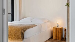 A minimalist bedroom with a bed, a bedside table with a lamp, and a view of the outside. - Chic Stay in Limpertsberg Near City Center (Luxembourg)