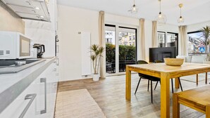 A modern kitchen with a microwave, stove, and dining area with a table and chairs. - Chic Stay in Limpertsberg Near City Center (Luxembourg)