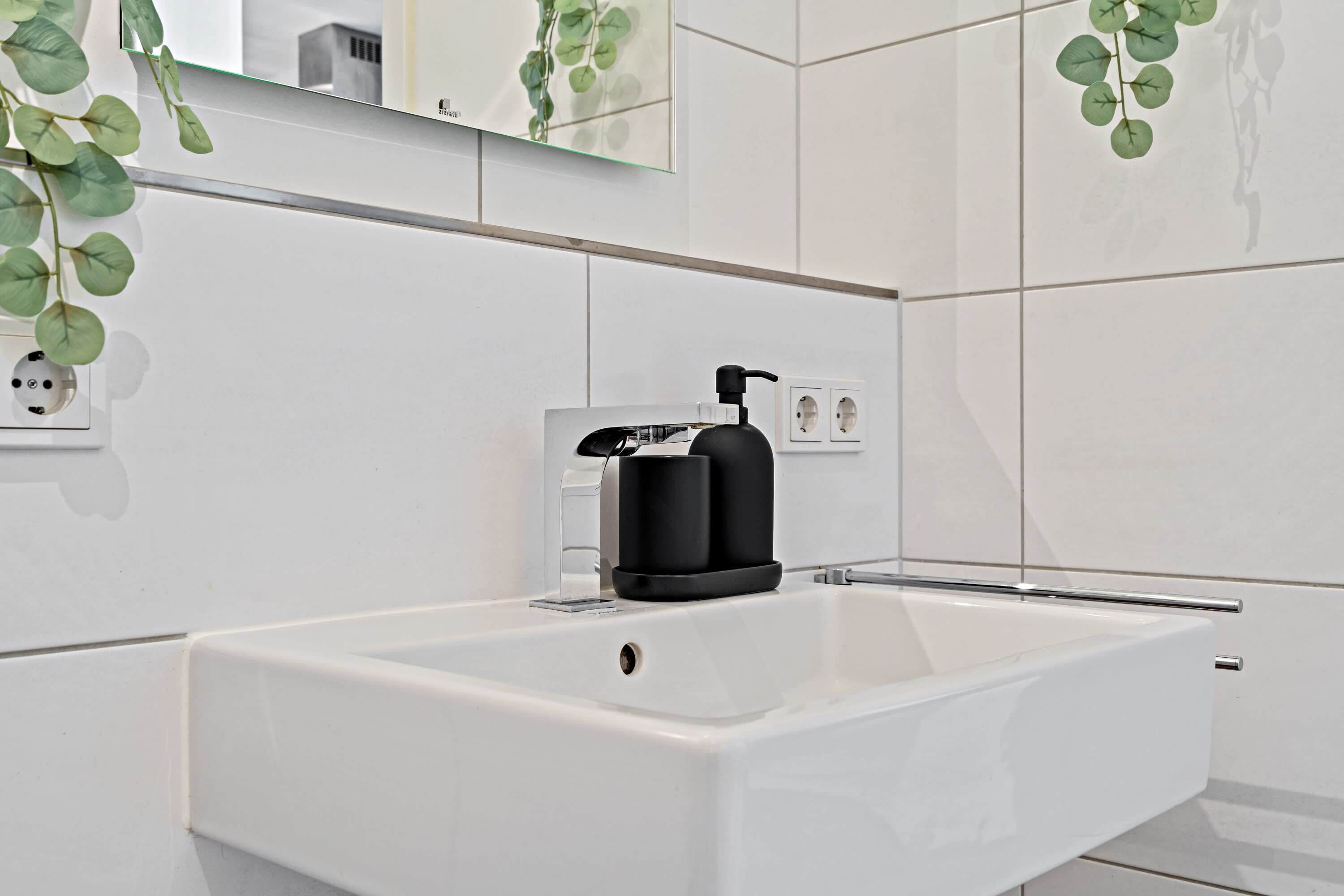 A modern bathroom with a white sink, black faucet, and a mirror above.