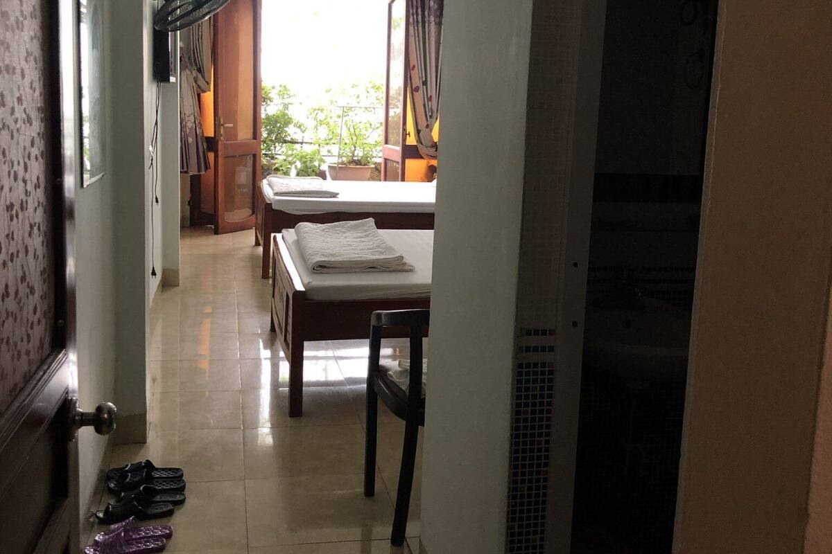 Un couloir mène à une salle à manger où se trouvent une table et des chaises, un ventilateur et une porte avec un paillasson.