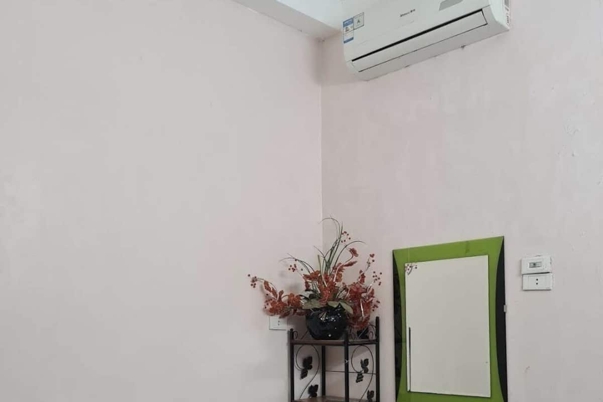 Un lit simple avec un matelas blanc et un vase décoratif posé sur une étagère en métal.