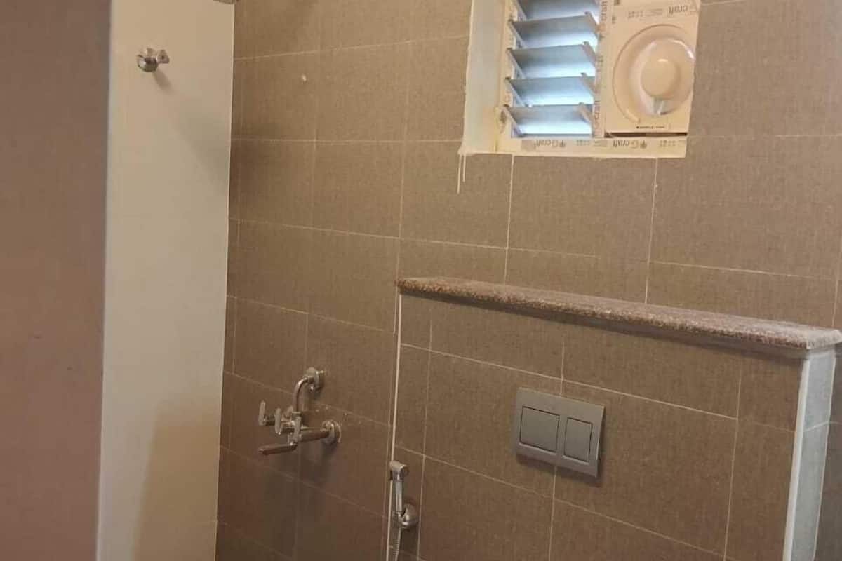 A bathroom with a shower, a toilet, and a small window with blinds.
