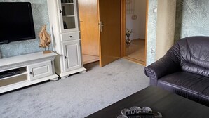 Un salon avec un téléviseur, un meuble, un canapé et une table basse.