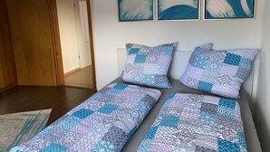 Une chambre à coucher avec un lit, deux oreillers et un mur orné de trois tableaux abstraits.