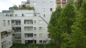 Een meerlaags woongebouw met balkons, een binnentuin en omliggend groen.