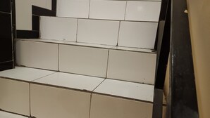 A set of white tiled stairs with a black frame on the right side. - OYO 93485 Hotel Kenzie Sentani (Sentani)