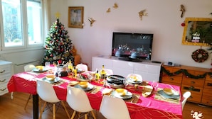 Comedor con árbol de Navidad, televisor y pared decorada.