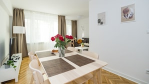 Een moderne eethoek met een houten tafel, beige stoelen en een vaas rode rozen.