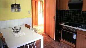 A compact kitchen with a white table, a black stove, and wooden cabinets.