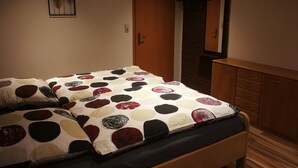 A bedroom with a bed, a wooden dresser, and a door leading to a bathroom.