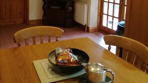 Un coin repas comprenant une table en bois, des chaises, un téléviseur et une fenêtre donnant sur un paysage agréable.