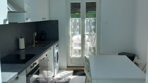 A modern kitchen with a built-in oven, a washing machine, and a dining area with a table and chairs.