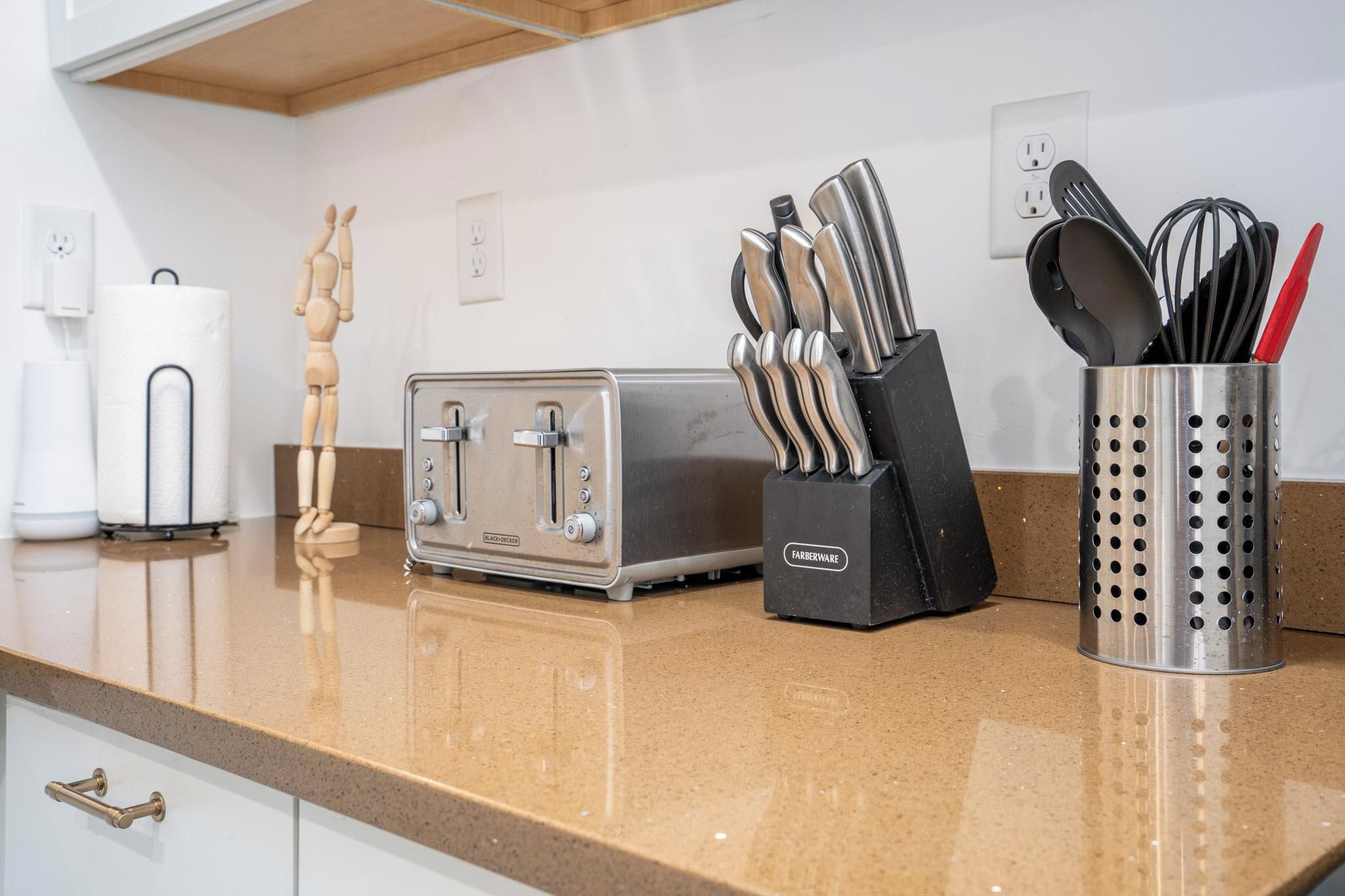 Eine Küchenarbeitsplatte mit einem Toaster, einer Holzfigur, einem Messerblock und einem Papierhandtuchhalter.