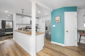 A modern kitchen with white cabinets, a stainless steel refrigerator, and a teal accent wall.