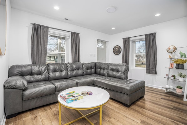 A modern living room with a sectional sofa, a round coffee table, and a bookshelf.