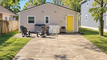 A single-story house with a front porch, a yellow door, and a concrete driveway.