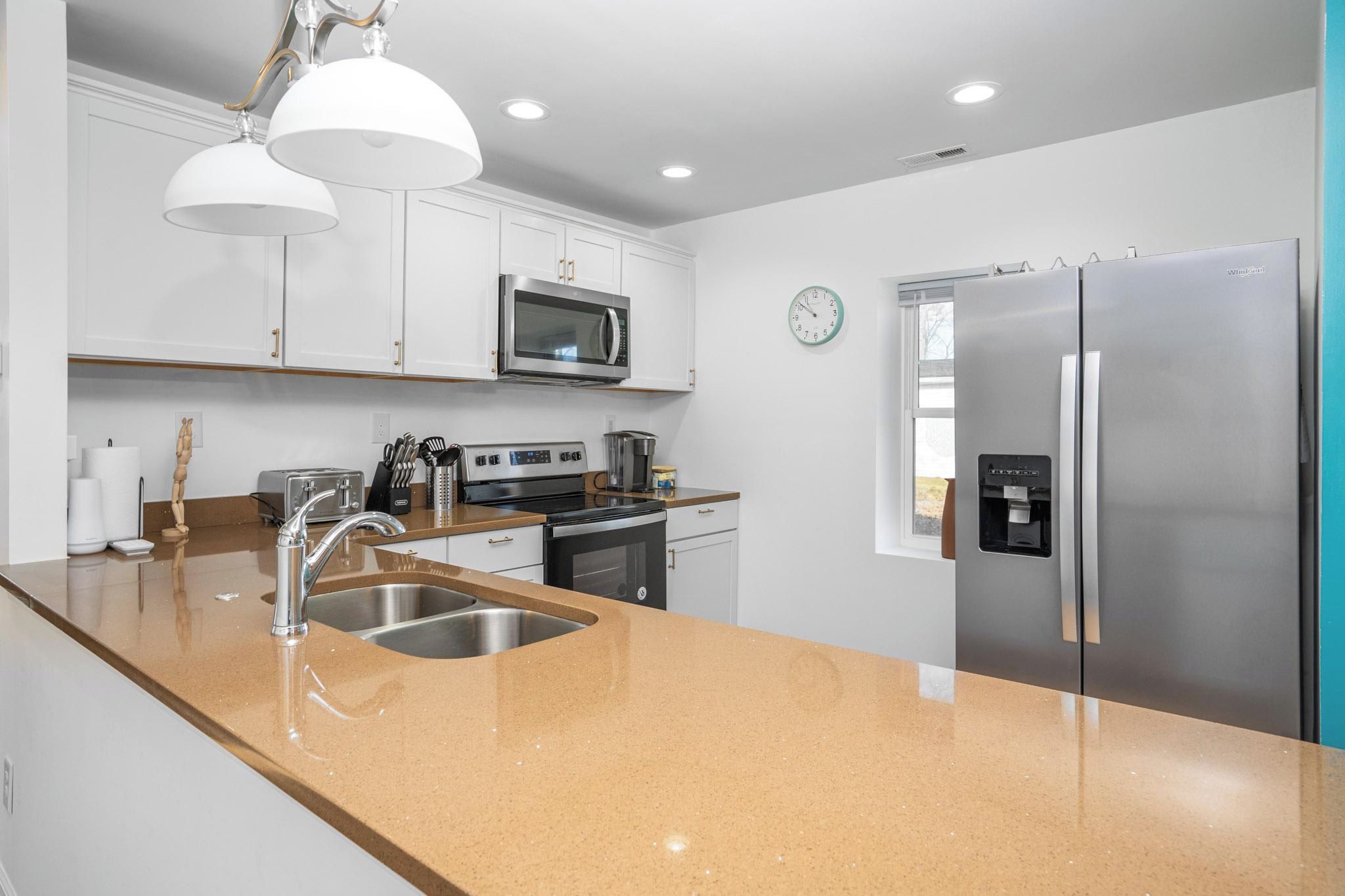 A modern kitchen with stainless steel appliances, a double sink, and a clock on the wall.