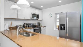 A modern kitchen with stainless steel appliances, a double sink, and a clock on the wall.