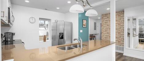 A modern kitchen with a central island, stainless steel appliances, and a pendant light fixture.