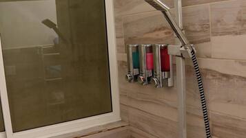 A shower area with a window, a handheld showerhead, and a wall-mounted faucet.