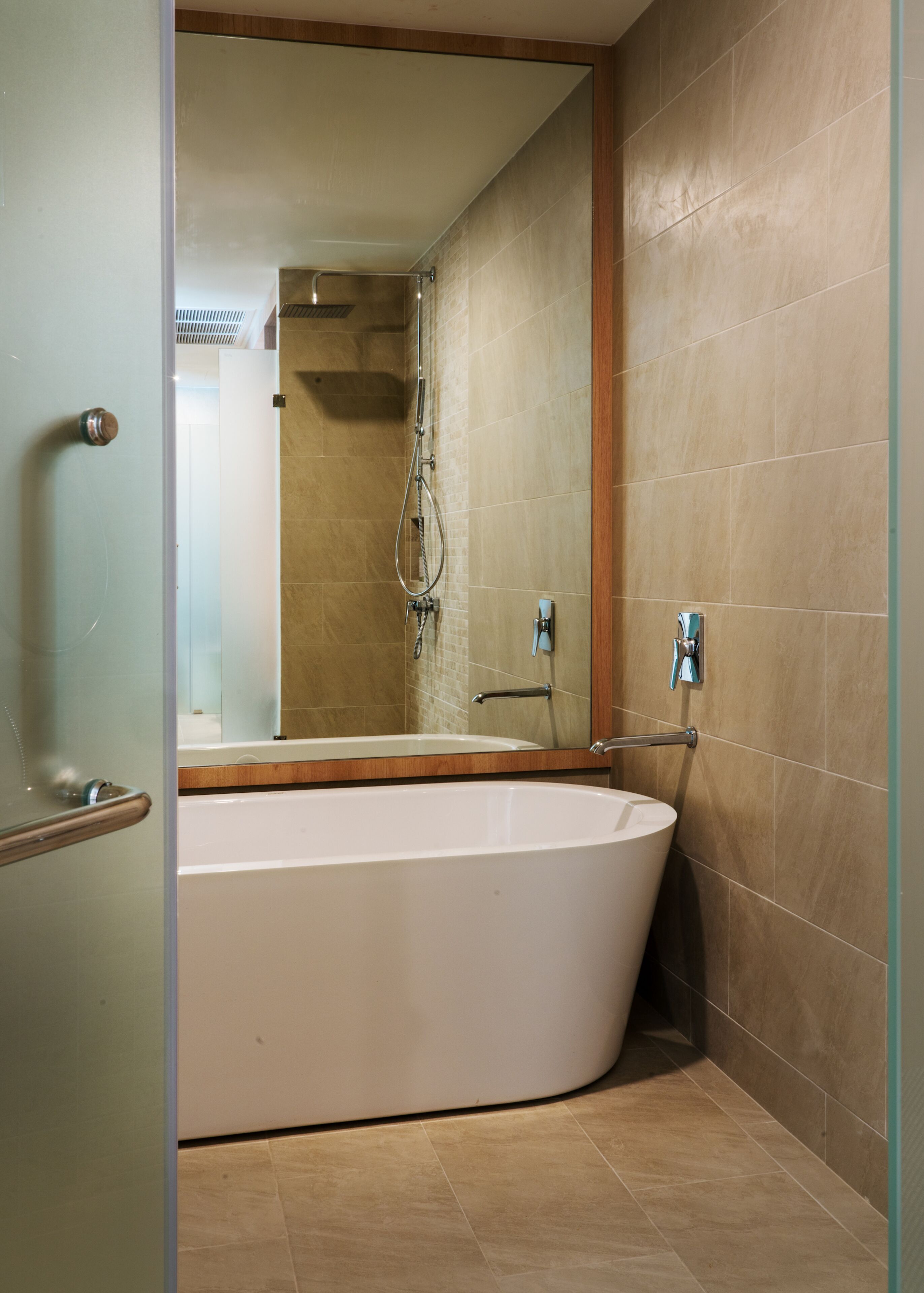 A modern bathroom with a freestanding bathtub, a glass shower enclosure, and a wooden vanity.