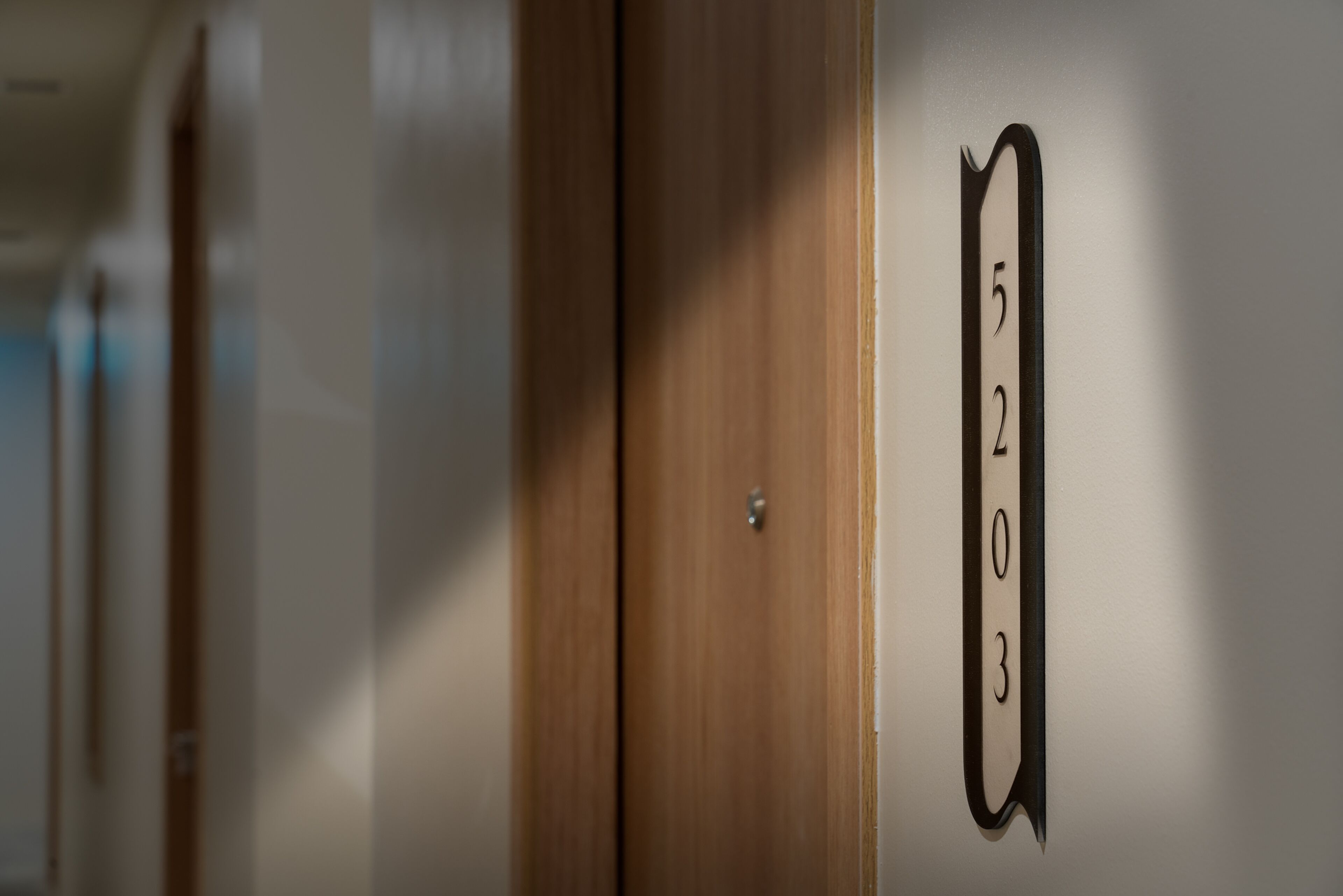 A hotel room with a wooden door and a number sign indicating room 5203.