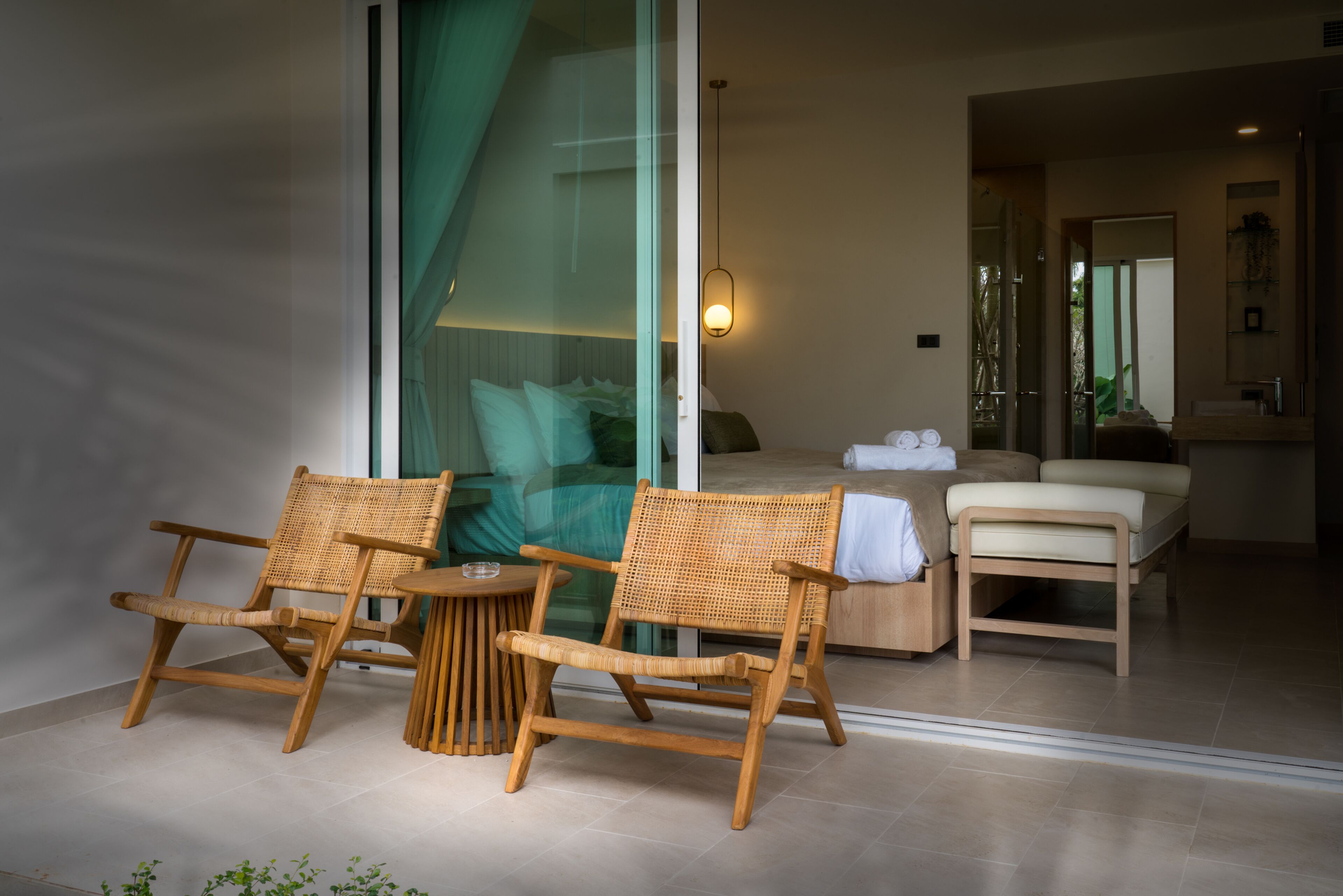 A modern room with a glass door leading to a balcony, a wooden chair, a small round table, and a sofa with a cushion.