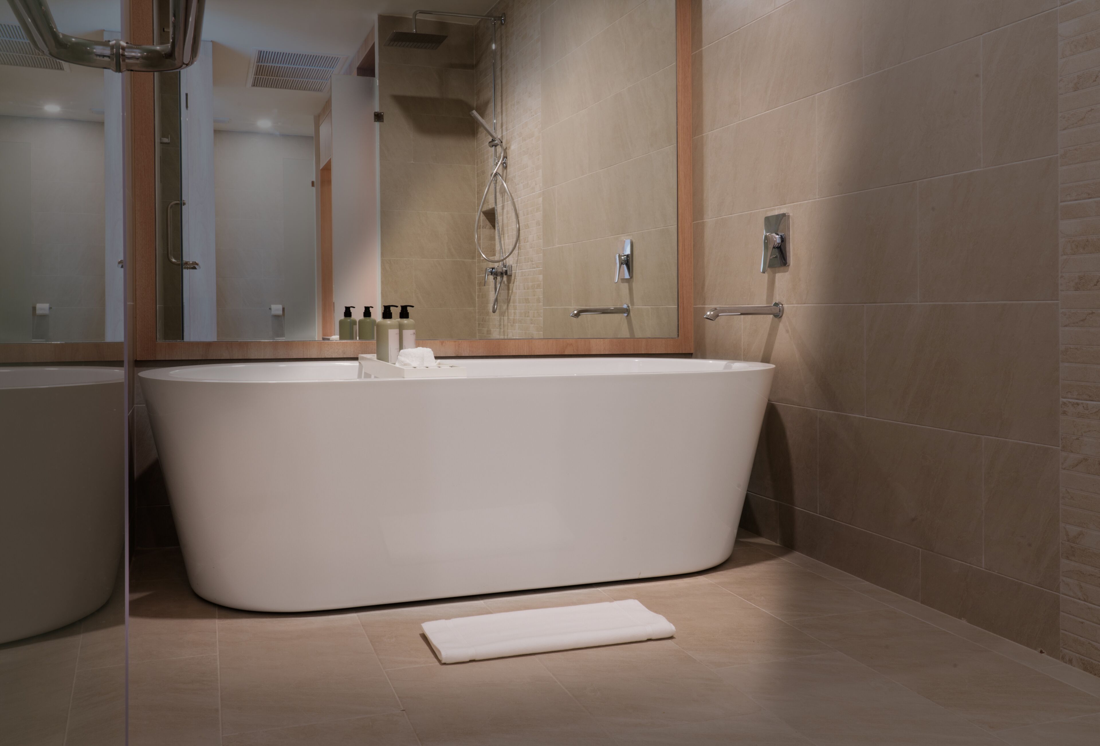 A modern bathroom with a freestanding bathtub, a large mirror, and a shower area.