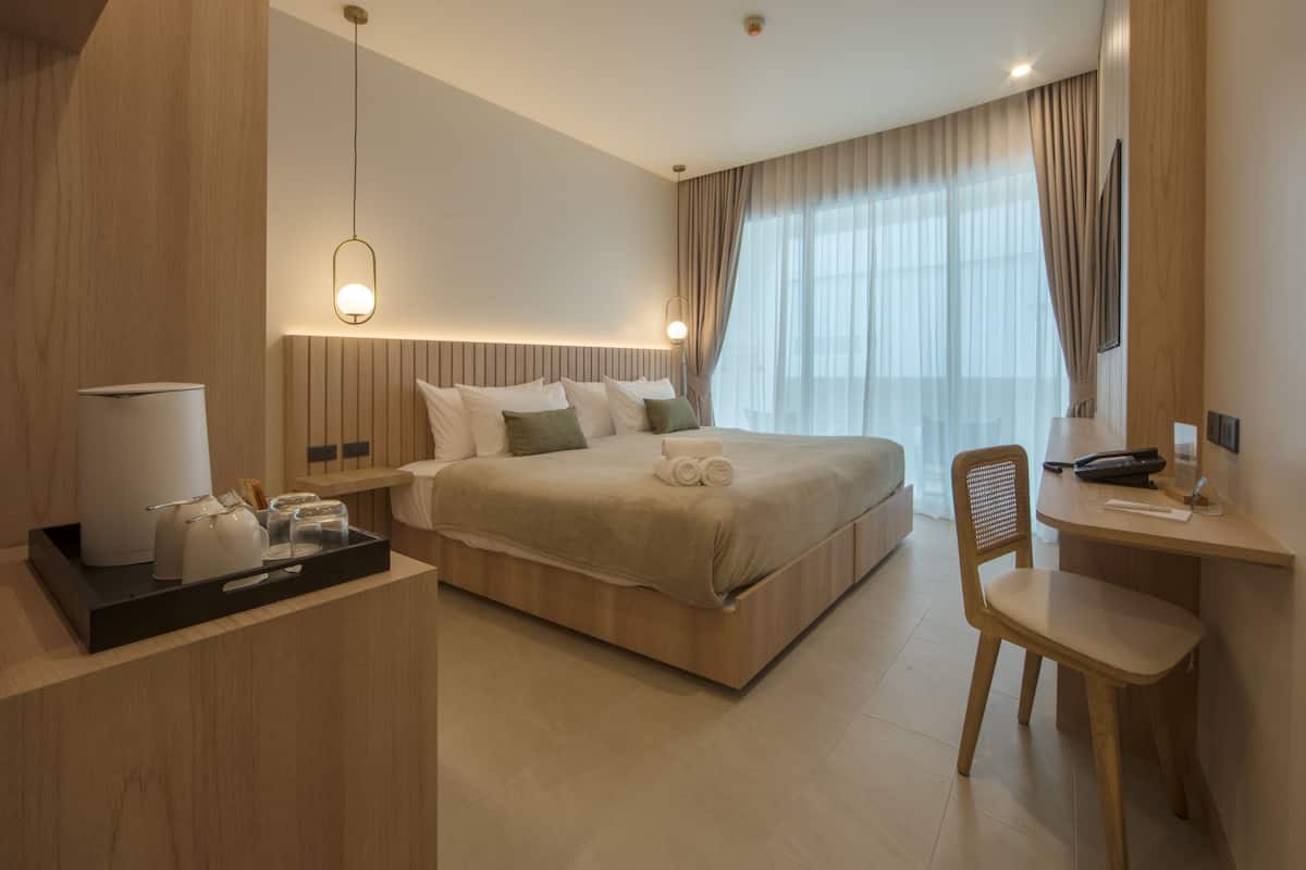 Una habitación de hotel moderna con una cama grande, una mesita de noche y un escritorio con una silla.
