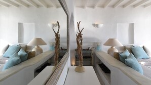 Een moderne woonkamer met een centrale salontafel, twee banken met kussens, een spiegel en wandlampen.