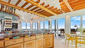 A spacious kitchen with a wooden island, large windows, and a view of the beach.