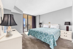 A bedroom with a bed, a nightstand, a lamp, a sculpture, and a view of the balcony.